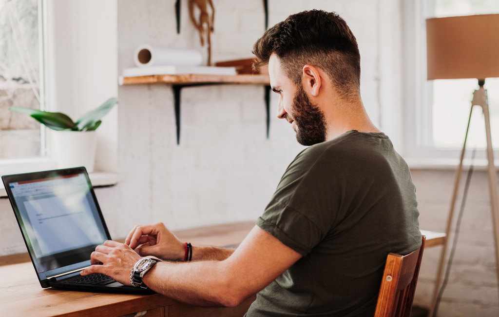Hombre sentado digitando en un computador portatíl